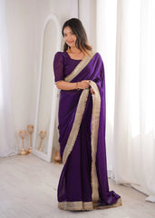 Woman wearing a purple saree with gold border indoors.