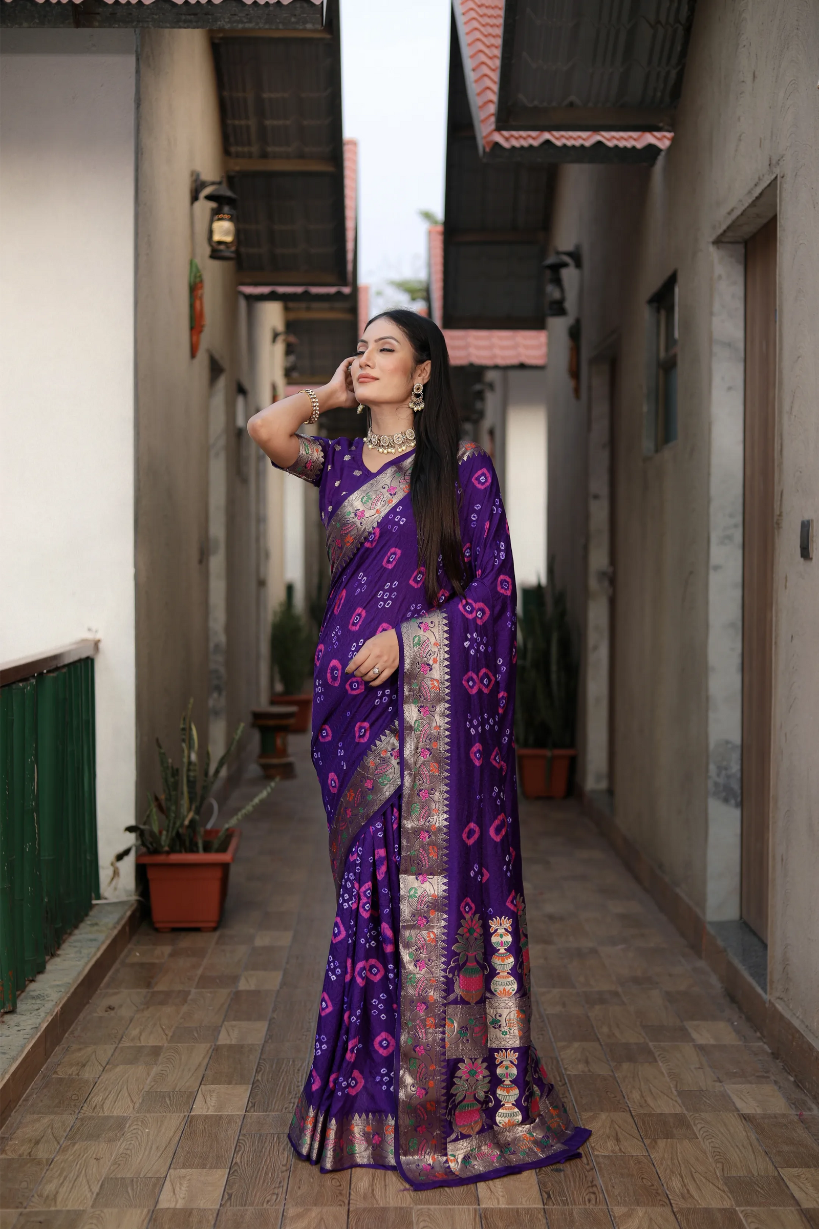 Woman in a purple saree standing in an alleyway