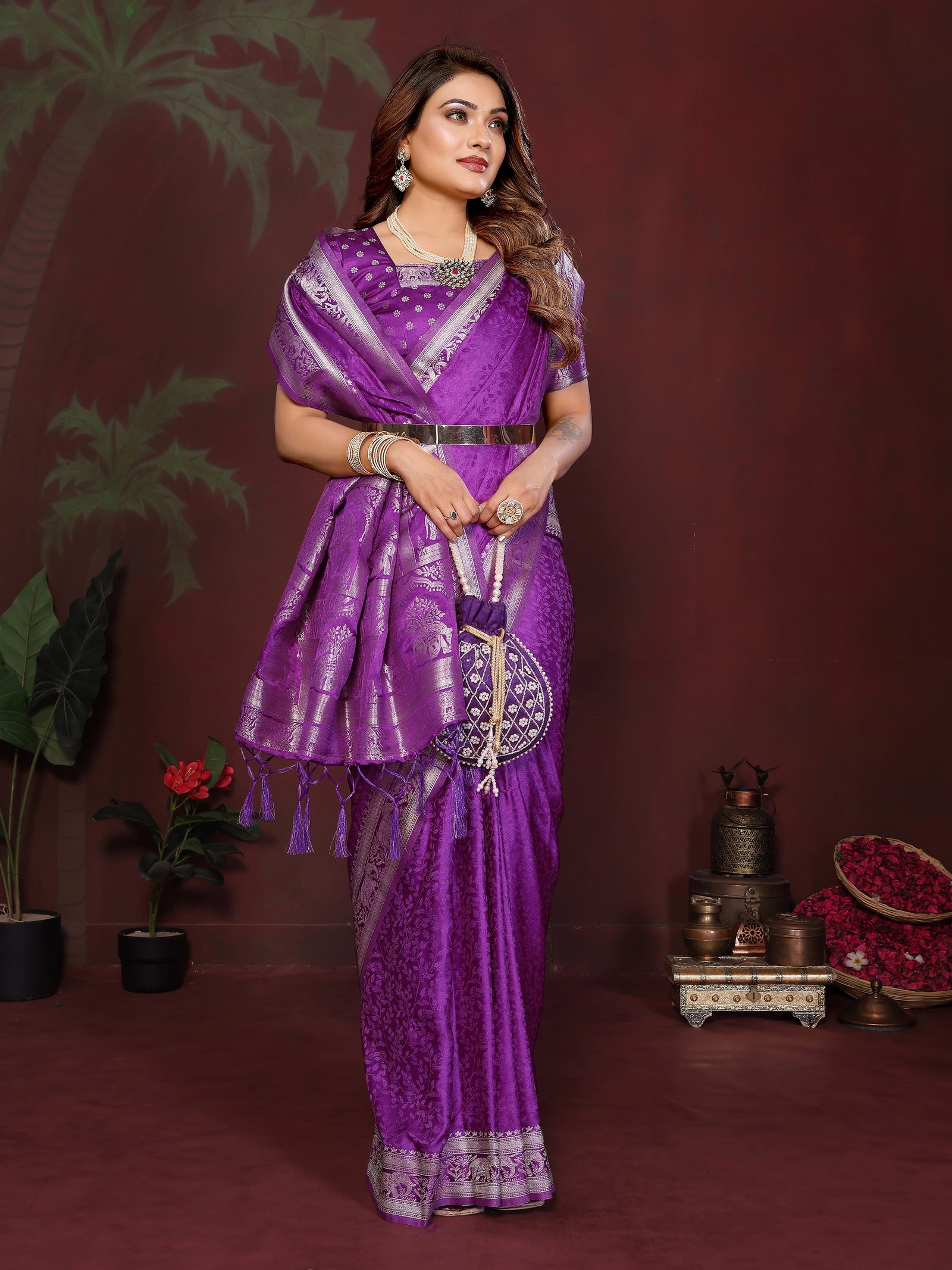 Woman in a purple saree with silver patterns against a dark background