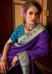 Woman wearing a traditional purple and blue saree with jewelry indoors.