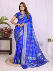 Woman wearing a blue saree with floral patterns in a room setting.