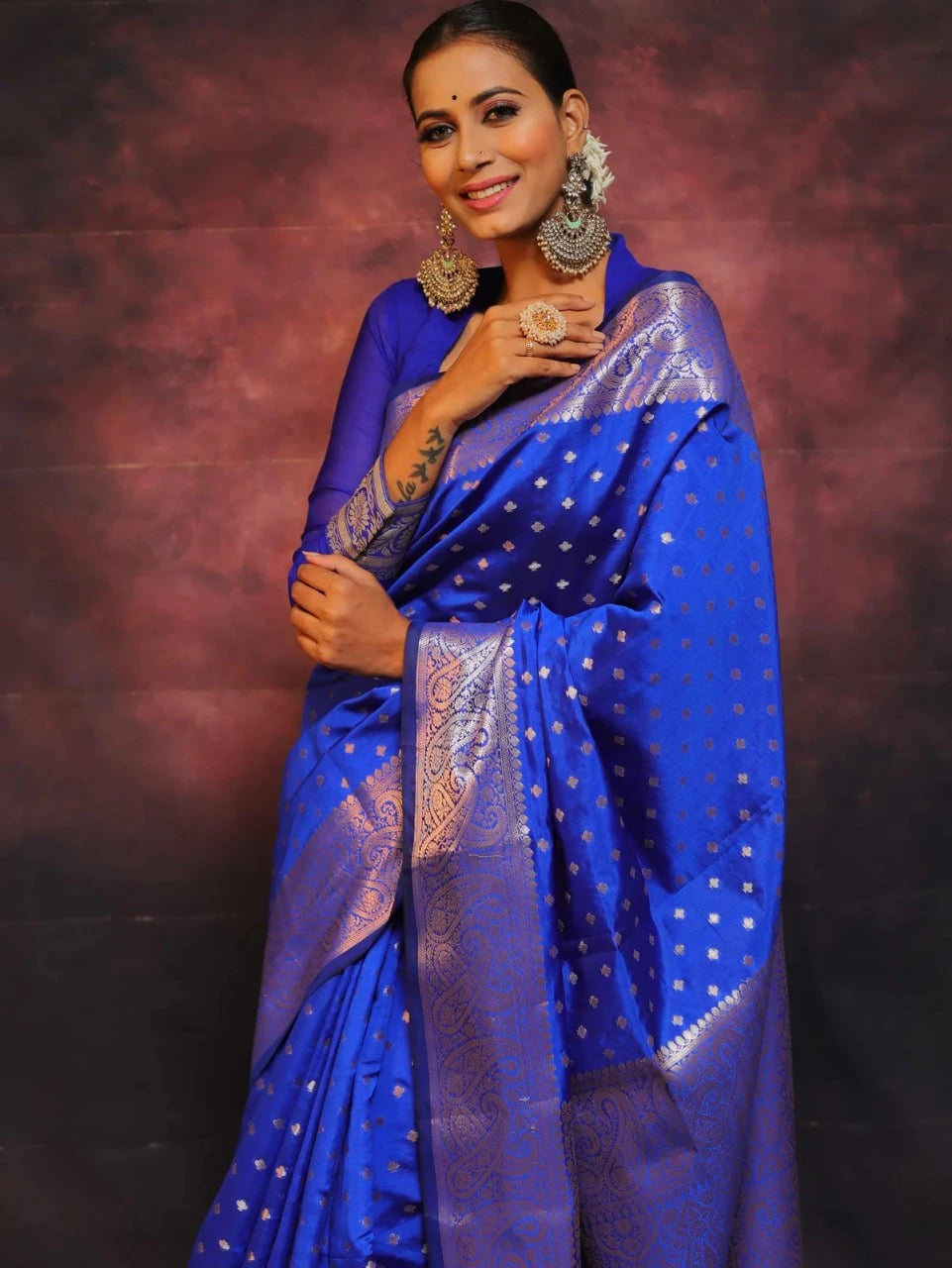 Woman wearing a blue saree with a patterned border against a dark background