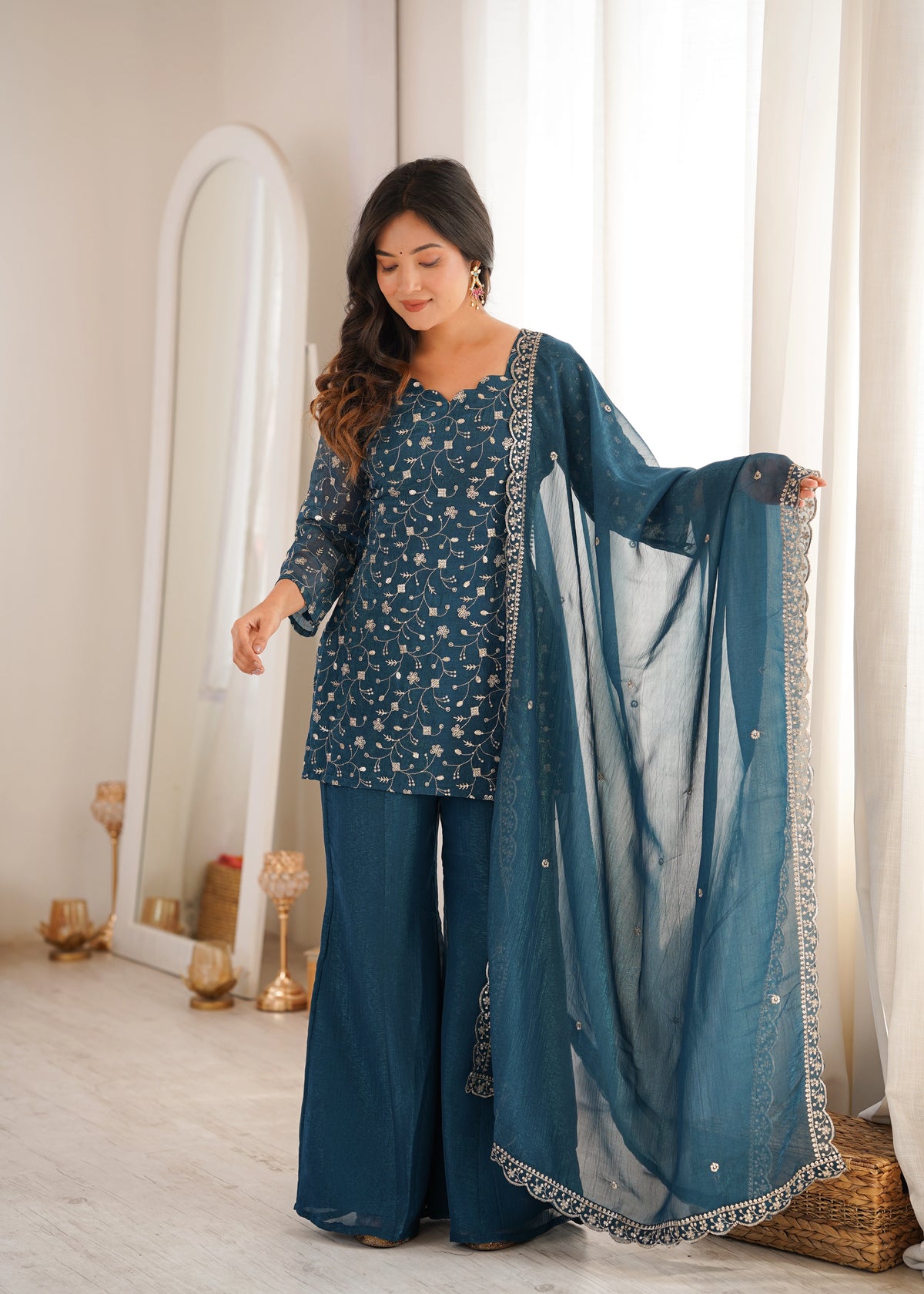 Woman in a blue traditional outfit with a matching dupatta in a well-lit room.