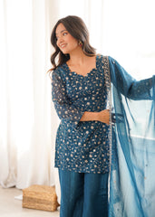 Woman in a blue traditional outfit with a matching dupatta, standing indoors.