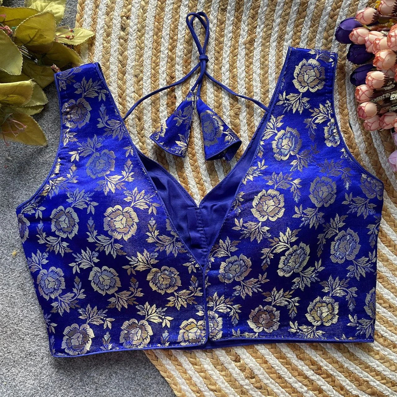 Blue floral embroidered top on a textured surface with flowers in the background