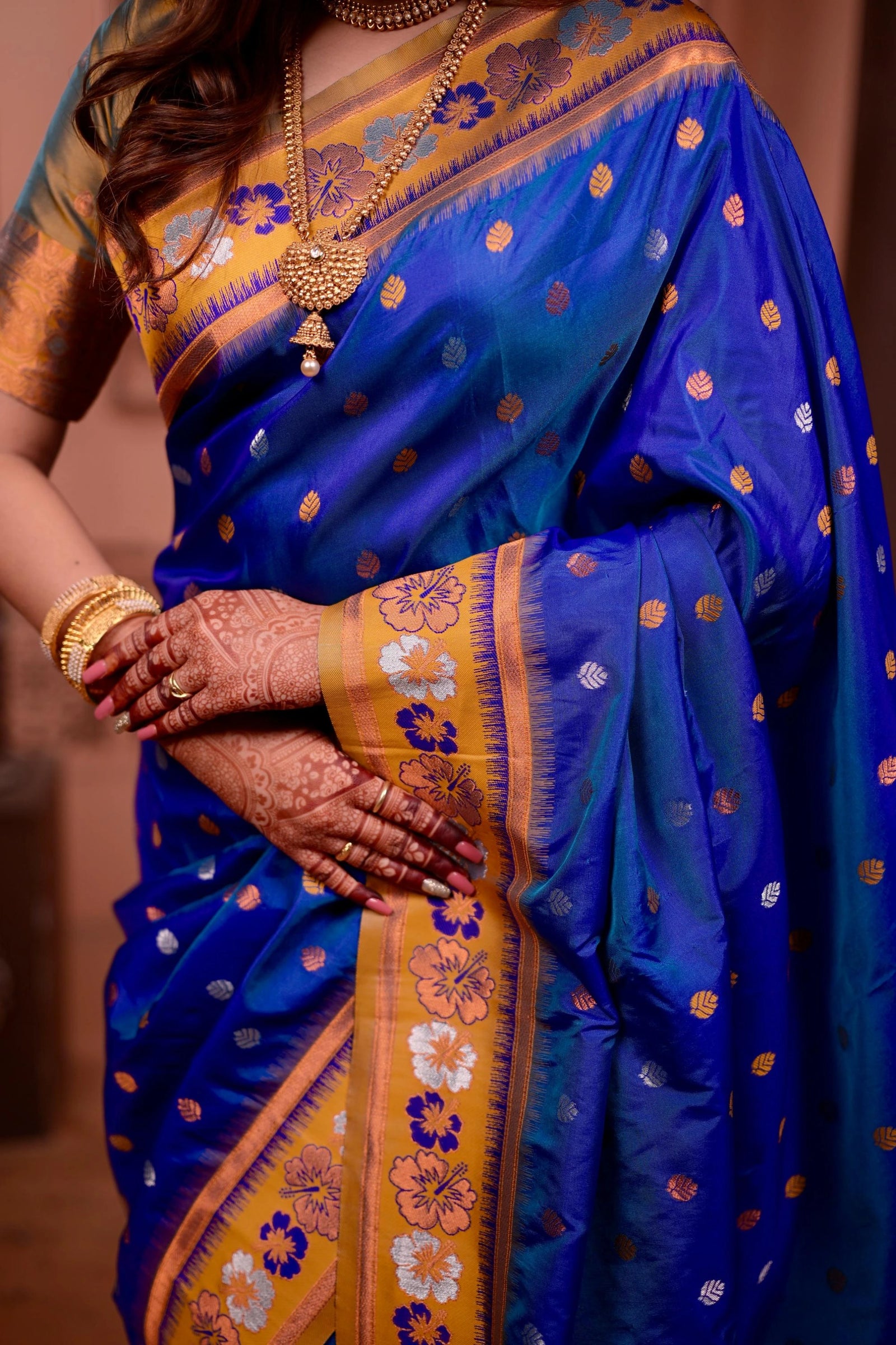 Blue saree with gold and yellow border held by a person