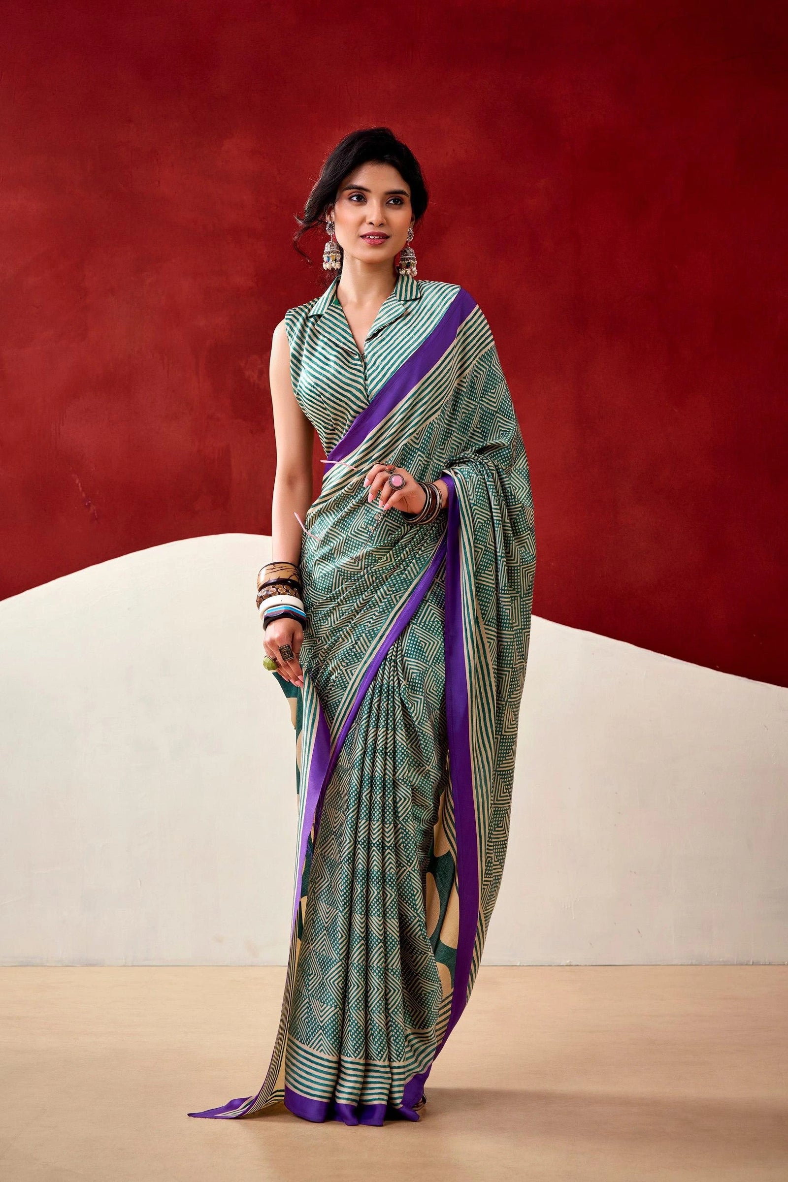 Woman wearing a green and purple saree against a red and beige background