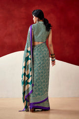 Woman wearing a green and purple saree with a red background