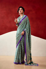 Woman wearing a green and purple saree with a red and beige background