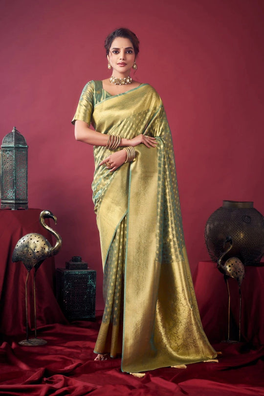 Woman in a gold saree with green blouse against a red background