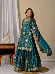 Woman wearing a teal embroidered traditional outfit with a beige background