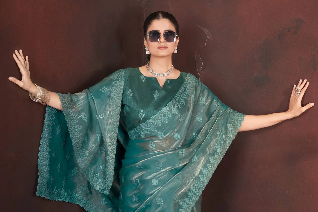 Woman wearing a teal saree with a brown background