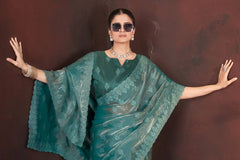 Woman wearing a teal saree with a brown background