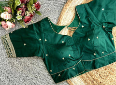 Green blouse with gold embroidery on a textured surface with flowers.