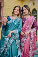 Two women in traditional sarees standing together with a decorative background.