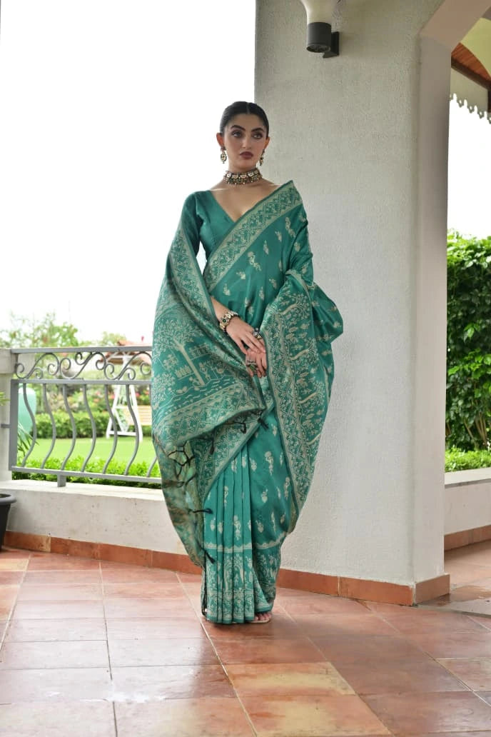 Woman wearing a green saree with a white wall and balcony in the background