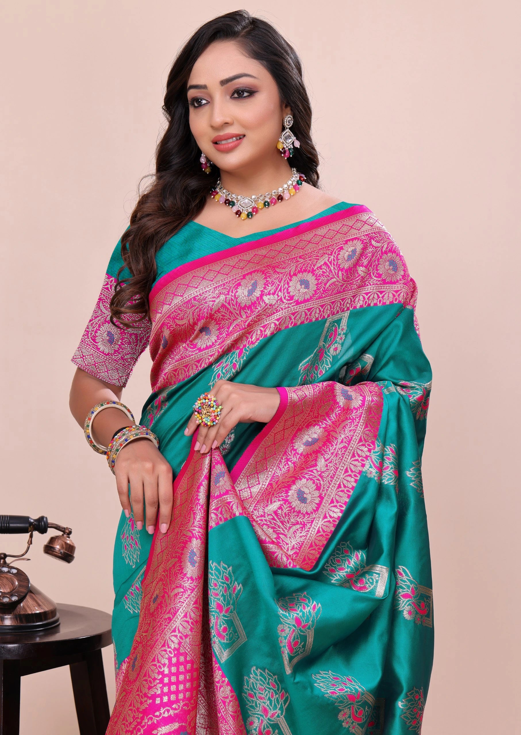Woman wearing a green and pink saree with a beige background