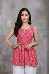 Woman wearing a pink patterned top against a gray concrete wall