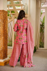 Person wearing a pink traditional outfit with floral patterns in an indoor setting.