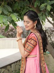 Woman in a pink traditional outfit with a floral headpiece, standing outdoors.