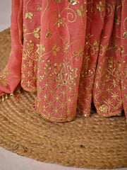 Pink fabric with gold embroidery on a textured surface