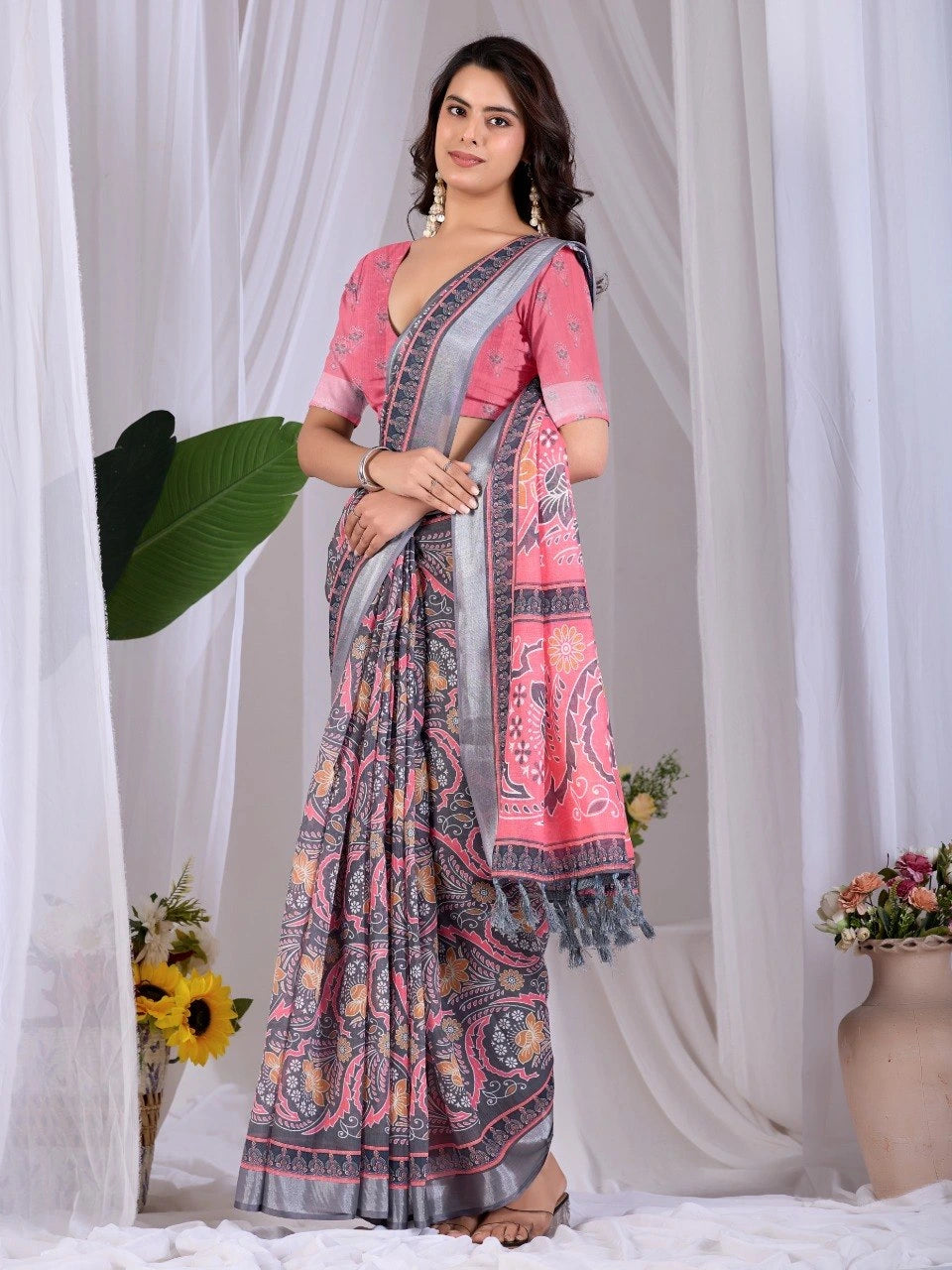 Woman wearing a pink and gray saree with a white curtain background