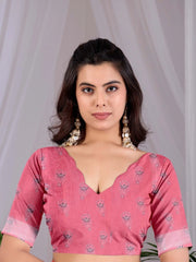 Woman wearing a pink blouse with floral patterns against a plain background