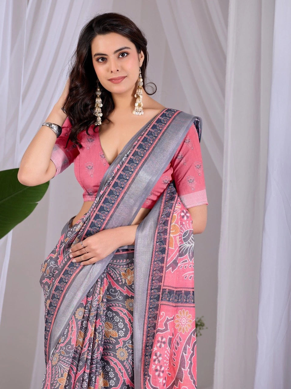 Woman wearing a pink and gray saree with a white curtain background