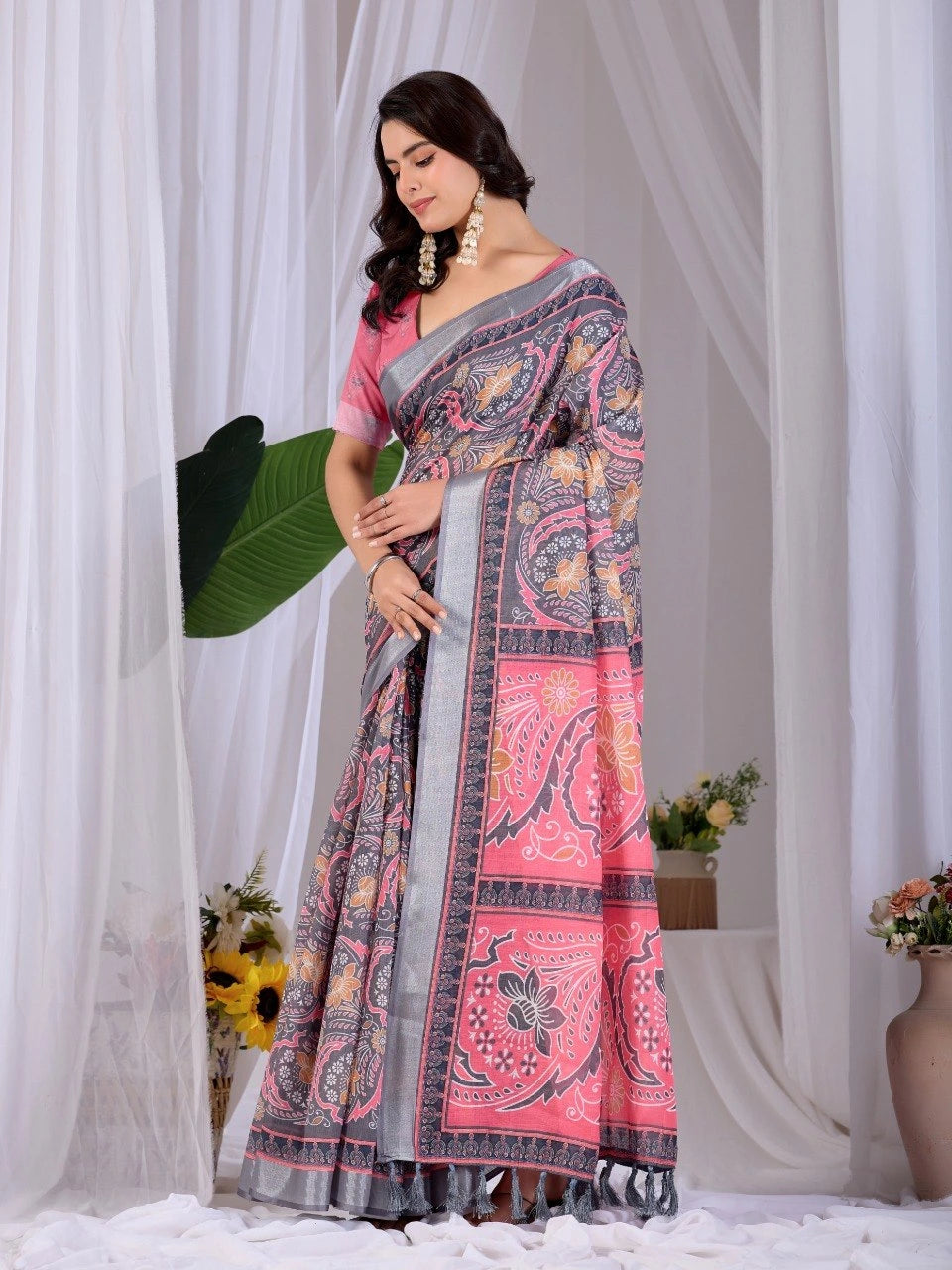 Woman wearing a pink and gray saree with a white curtain background