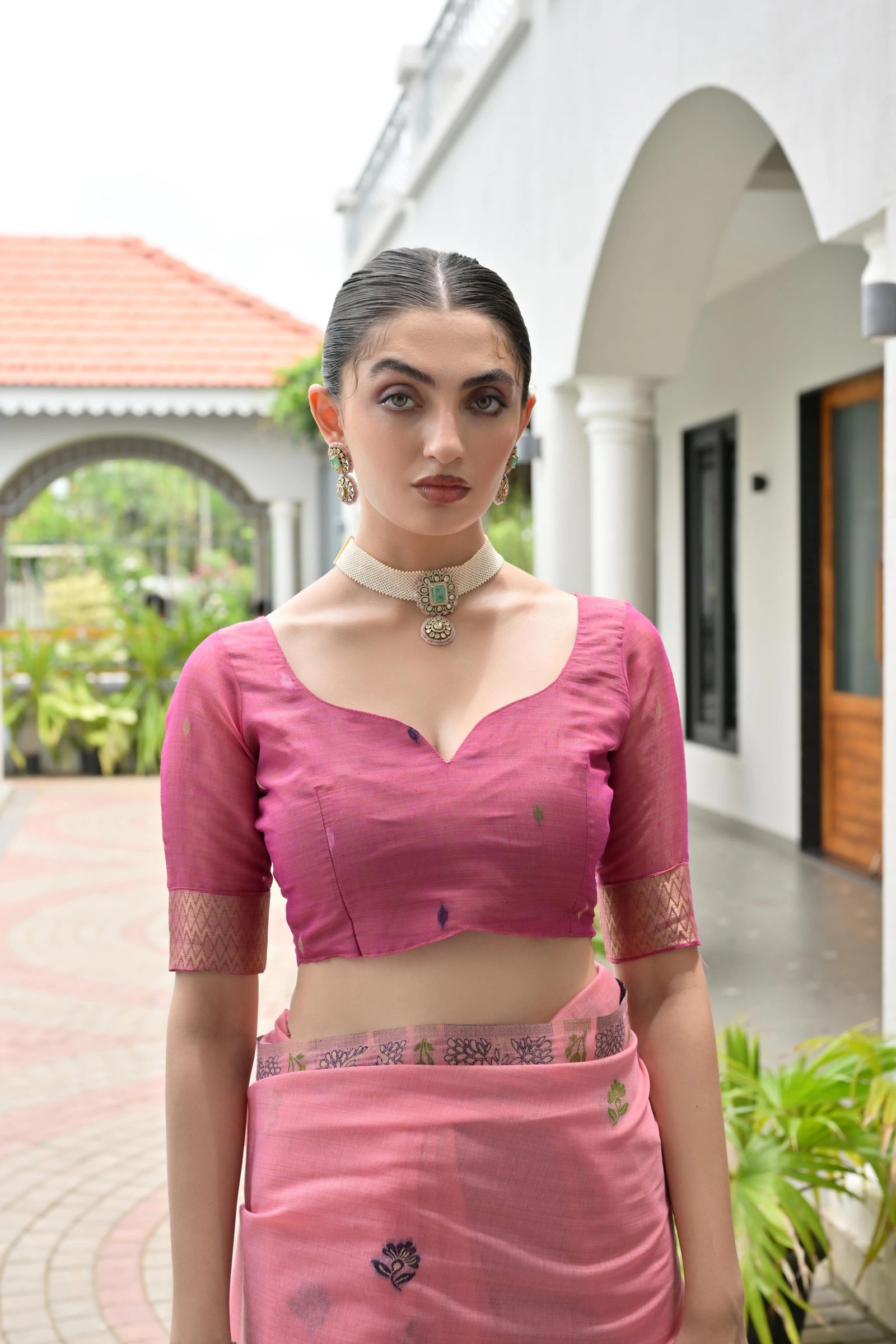 Woman in a pink traditional outfit standing outdoors.