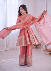 Woman in a traditional pink embroidered outfit with a white curtain background