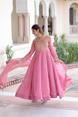 Woman in a pink traditional outfit standing in front of an architectural building.