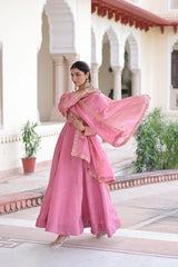 Woman in a pink traditional outfit standing in front of an architectural building.