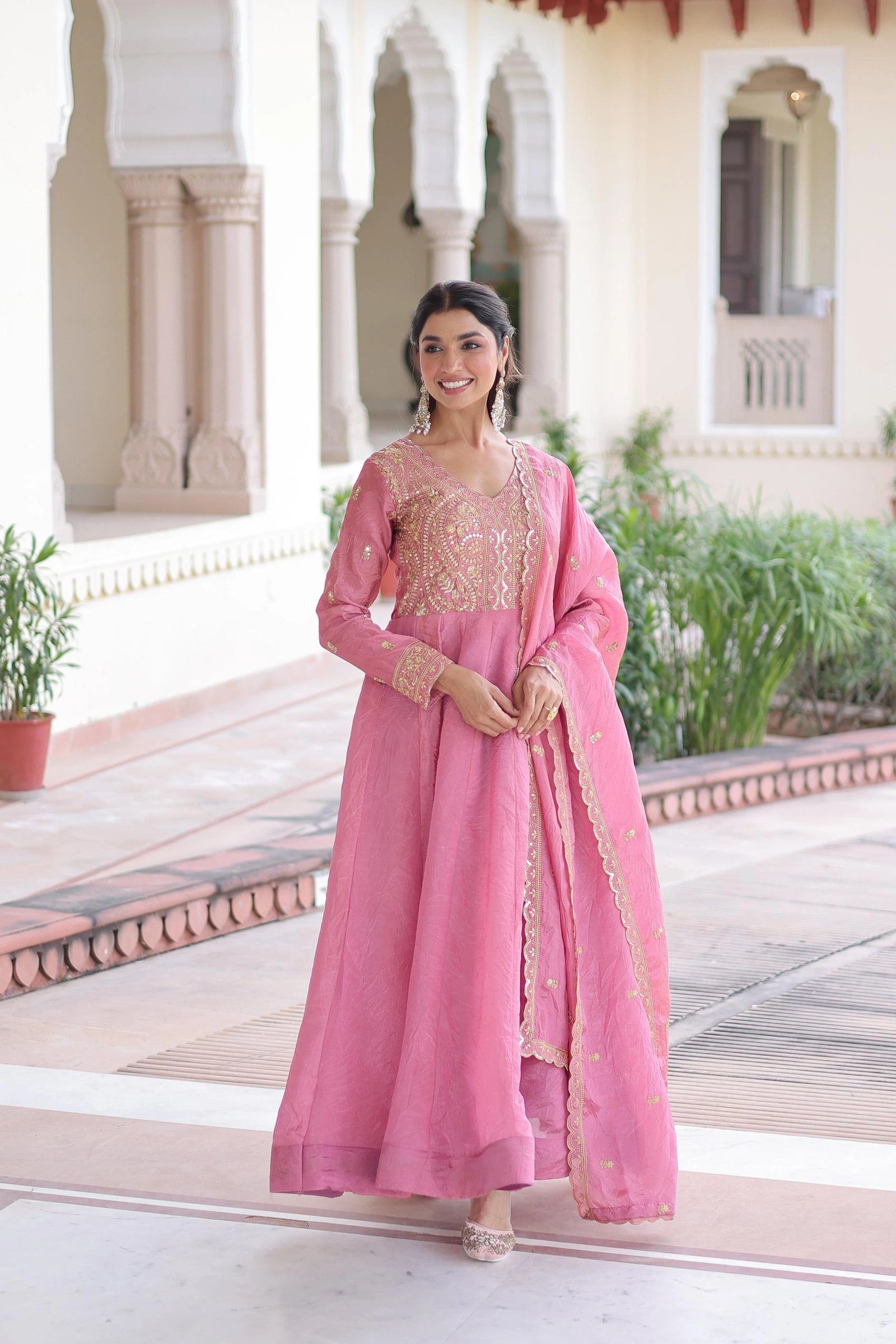 Woman in a pink traditional outfit standing in front of an architectural building.