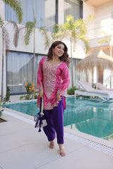 Woman in pink and purple traditional outfit standing by a poolside.