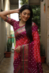 Woman in a traditional pink saree with a patterned blouse, standing outdoors.