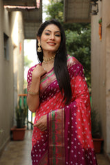 Woman in a traditional pink saree with a pattern, standing outdoors.