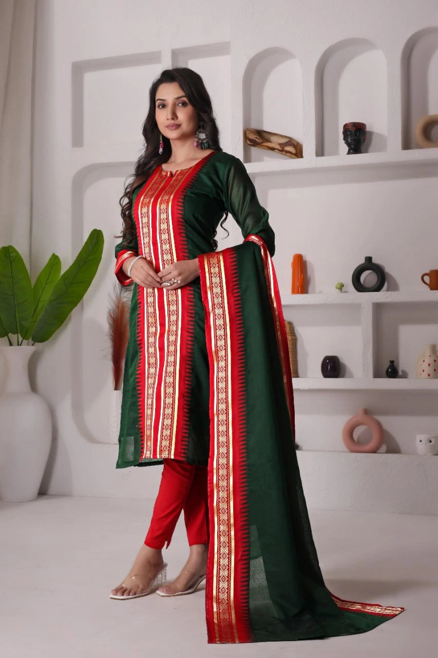 Woman wearing a green and red traditional outfit in a minimalistic room.
