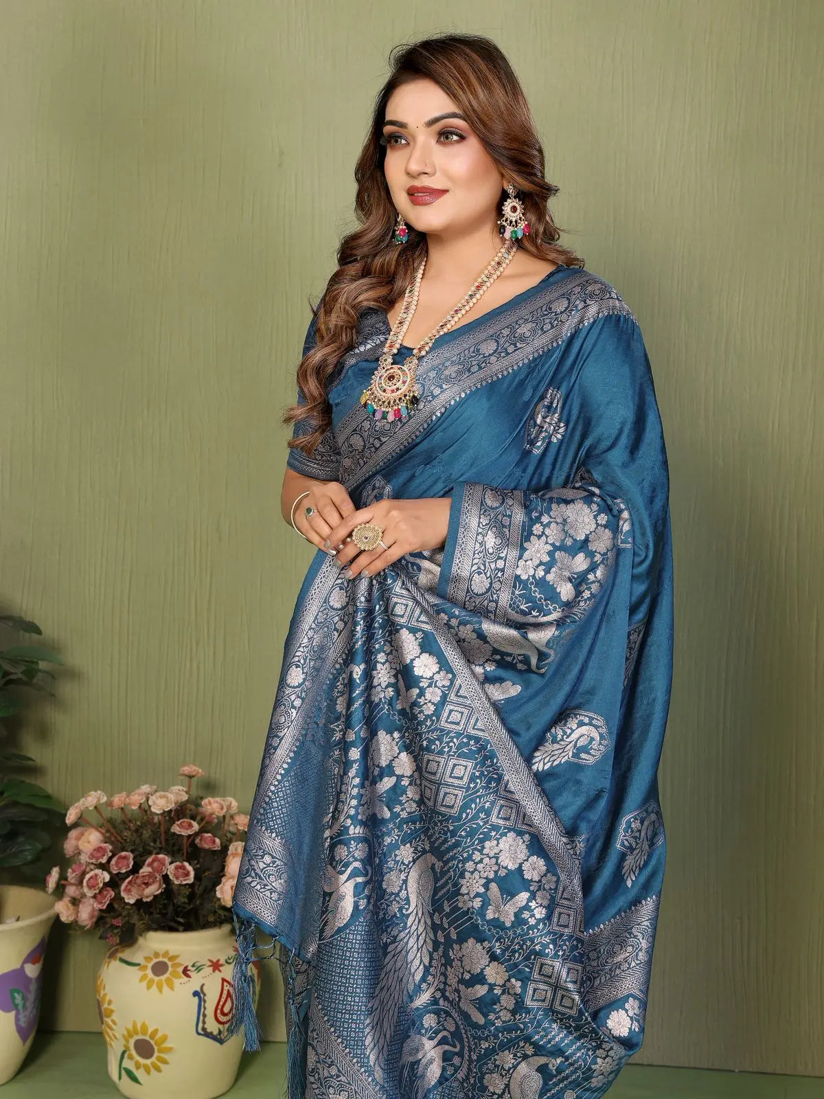 Woman wearing a blue saree with intricate patterns against a green background