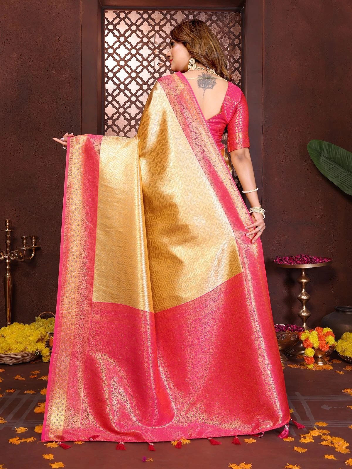 Woman wearing a pink and gold saree in a decorated indoor setting