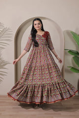 Woman wearing a floral dress standing in front of an archway with plants on either side.