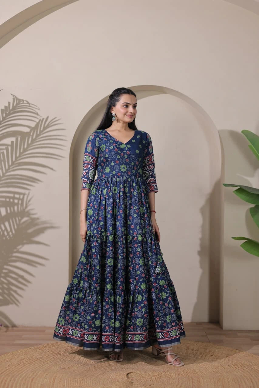 Woman wearing a blue floral dress standing in front of an archway with plants.
