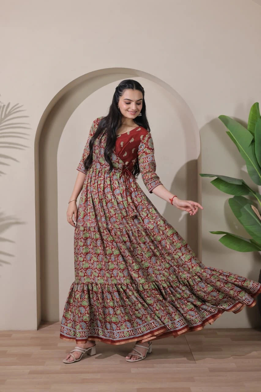 Woman in a patterned dress standing in front of an archway with plants on either side.