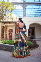 Woman in a colorful traditional outfit standing in an outdoor setting with architectural elements.