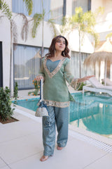 Woman in traditional outfit standing by a poolside with modern building and plants in the background