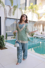Woman in traditional outfit standing by a poolside with modern building and plants in the background