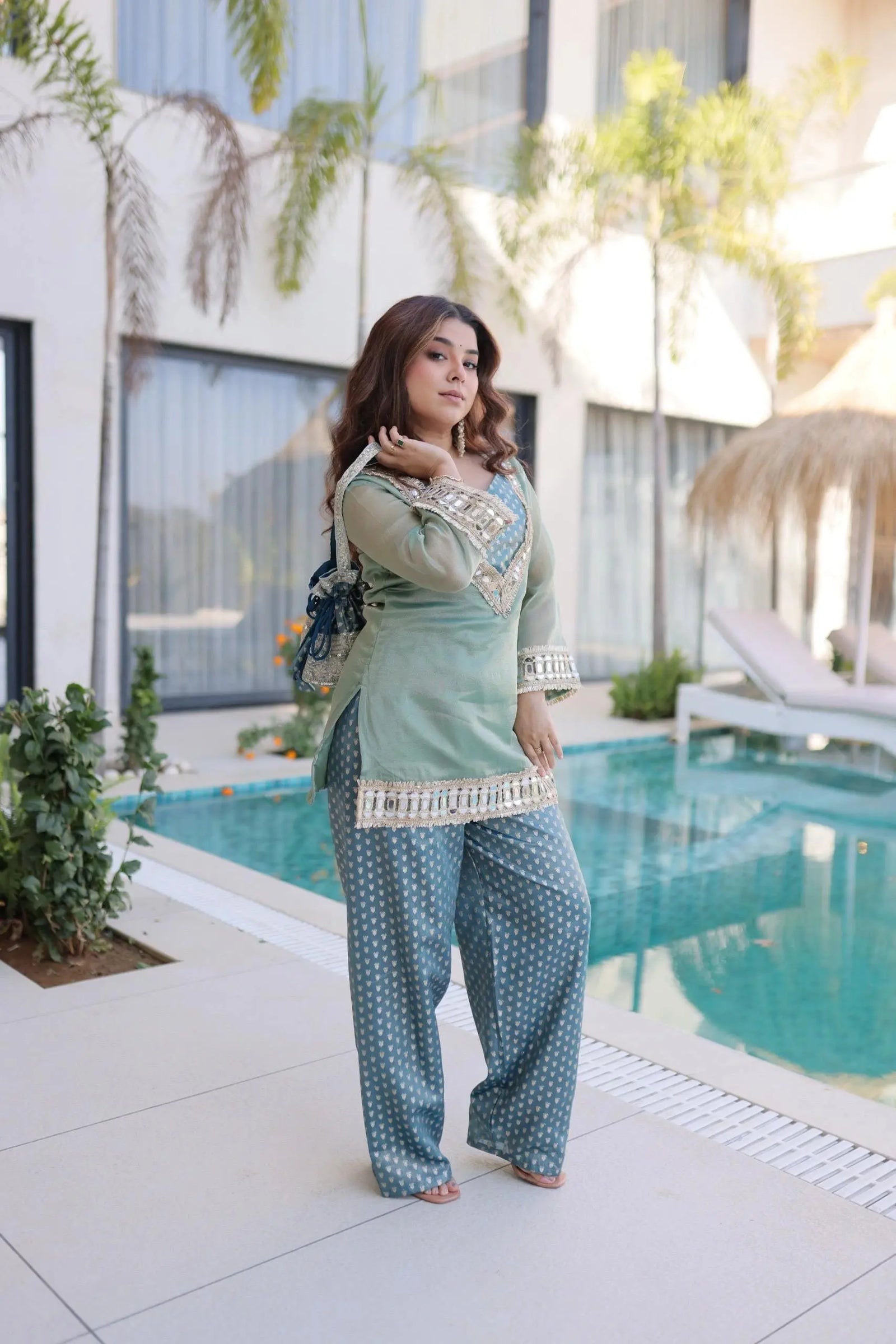 Woman in traditional outfit by a poolside with modern building in background
