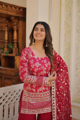 Woman in a red and pink traditional outfit with a matching dupatta, standing indoors.