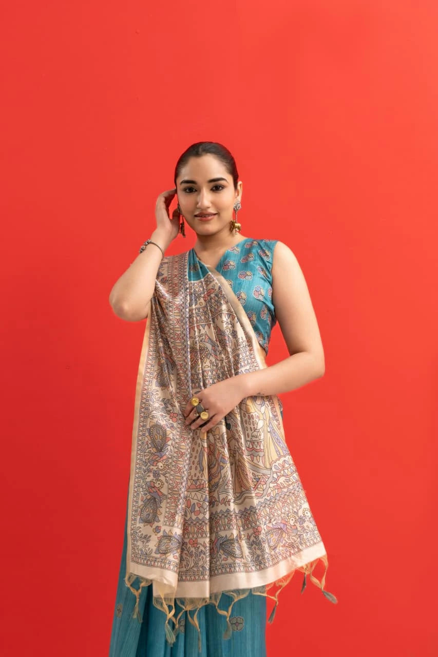 Woman wearing a blue traditional outfit with a patterned dupatta against a red background