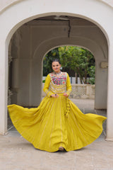 Woman in a yellow traditional outfit standing in an archway with greenery in the background